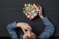 Boy eating Easter egg. Heart shaped box with colorful eggs in hand. Top view