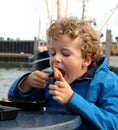 Boy eating Fish in Harbour Royalty Free Stock Photo
