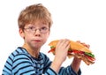 Boy eating large sandwich on white