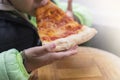 close up boy eating a piece of pizza on wooden background in outdoor Royalty Free Stock Photo