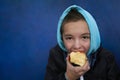 Boy eating red apple on blue background with copy space Royalty Free Stock Photo