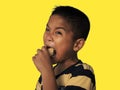 The boy eats hot dog solated on a yellow background. Embed clipping path. Junk food concept Royalty Free Stock Photo
