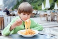 A boy eats italian spaghetti