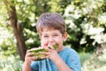 Boy eats watermelon outdoors