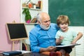 Boy from elementary school at the school yard. Grandfather and grandson. Friendly child boy with old mature teacher in Royalty Free Stock Photo