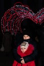 A boy embraces a girl against the background of the new year`s illumination of the arch of hearts