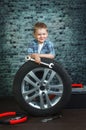 Boy is engaged in repair of wheels cars