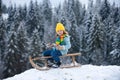 Boy enjoy a sleigh ride. Child sledding, riding a sledge. Children play in snow in winter. Outdoor kids fun for Royalty Free Stock Photo