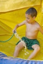 Boy enjoying a wet inflatable slide Royalty Free Stock Photo