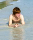 Boy enjoys lying in the spume of the tropical beach