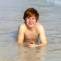 Boy enjoys lying in the spume of the tropical beach