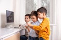 Boys enthusiastically draw on a computer using a tablet. The younger brother plays games on the phone. Older brother helps him