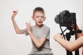Boy enthusiastically sings in front of the camera. Children`s hands with a camera in the frame. Young video blogger. White