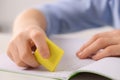 Boy erasing mistake in his notebook at white desk, closeup