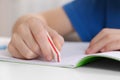 Boy erasing mistake in his notebook at white desk, closeup Royalty Free Stock Photo