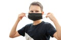 A boy of European appearance puts on a black antibacterial mask on a white background