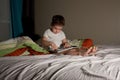 Boy in the evening on the bed of the parents reading a book Royalty Free Stock Photo
