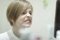 A boy examines cleaned teeth in front of a mirror