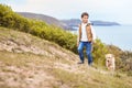 Boy Exercising Dog On Leash Walking Up Hill By Sea Royalty Free Stock Photo
