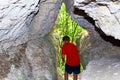 The boy exits the cave in the rock, the rear view.