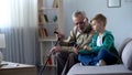 Boy explaining to grandpa how to use cell phone, simple technologies for old man Royalty Free Stock Photo