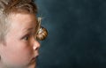 Boy face with big snail. Animal at home. Pet. Portrait of blond freckled child boy with snail on face. Sustainable