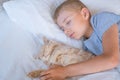 the boy falls asleep and hugs his ginger cat, who sleeps with him under the covers. children and pets. the cat sleeps Royalty Free Stock Photo