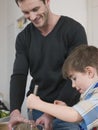 Boy And Father Cooking Food In Kitchen