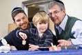 Boy with father and grandfather spinning dreidel Royalty Free Stock Photo