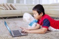 Boy feeding his dog while using laptop in his home Royalty Free Stock Photo