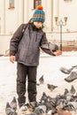 The boy feeds the pigeons on his hands, standing on the square Royalty Free Stock Photo