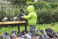 Boy feeds pigeons park bench lifestyle windbreaker spring