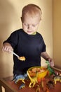 A boy feeds a toy dinosaur porridge from a spoon Royalty Free Stock Photo