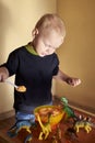 A boy feeds a toy dinosaur porridge from a spoon Royalty Free Stock Photo