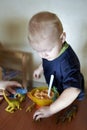 A boy feeds a toy dinosaur porridge from a spoon Royalty Free Stock Photo