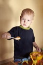A boy feeds a toy dinosaur porridge from a spoon Royalty Free Stock Photo
