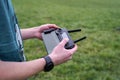 A boy in a field launches a quadcopter and controls it from the remote control