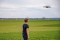 A boy in a field launches a quadcopter and controls it from the remote control