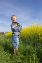 Boy field Rapeseed,happy boy standing in a grass near a field of rape in spring Royalty Free Stock Photo