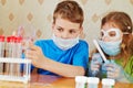 Boy fills chemical test tubes with specimen and girl watches after him