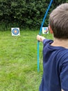 Boy fires arrow dart at a target with his bow