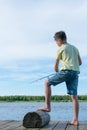 Boy fishes standing on the pier at the lake in the evening Royalty Free Stock Photo