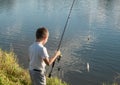 Boy fishing on a lake. Beautiful fish pond in Badin, near Banska Bystrica, Slovakia. Shining sun over the fish pond in summer day Royalty Free Stock Photo