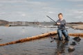 A boy with a fishing rod catches fish sitting on the river bank Royalty Free Stock Photo