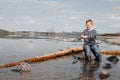 A boy with a fishing rod catches fish sitting on the river bank Royalty Free Stock Photo