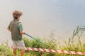 A boy with a fishing rod fishes on the lake,a river,a sea Royalty Free Stock Photo