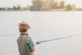 A boy with a fishing rod fishes on the lake,a river,a sea Royalty Free Stock Photo