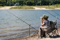 Boy with fishing rod sitting on the shore of the pond. Royalty Free Stock Photo