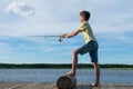 Boy fishing with spinning on the river, blue sky background Royalty Free Stock Photo