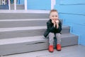 A boy of five, sits on the steps, smiles happy at life, poses on the camera Royalty Free Stock Photo